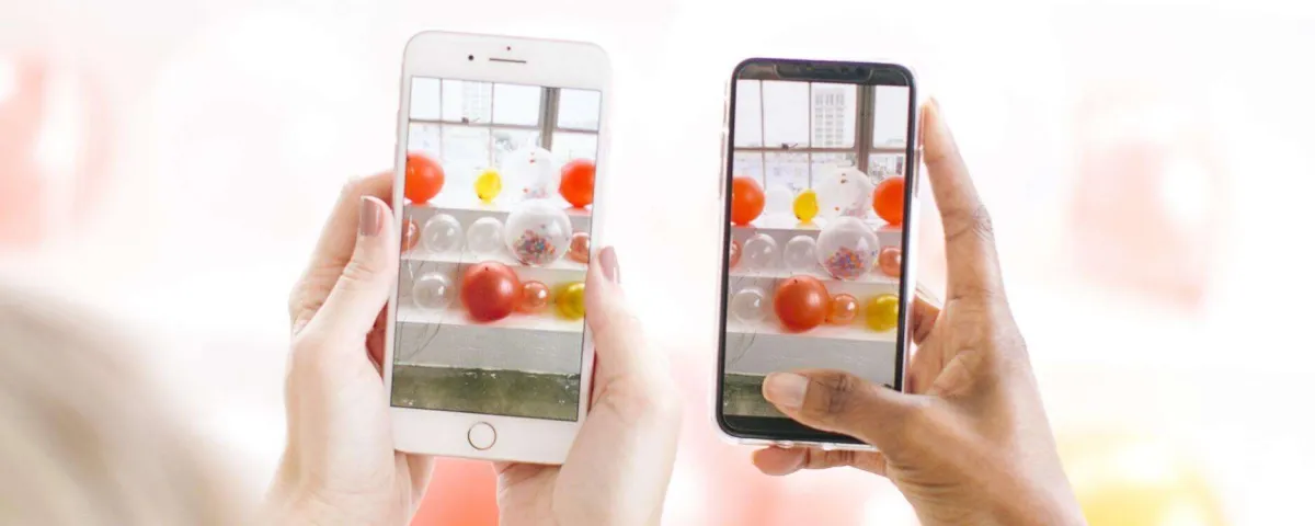 Two people holding up phones side by side, each screen showing the same scene being photographed.