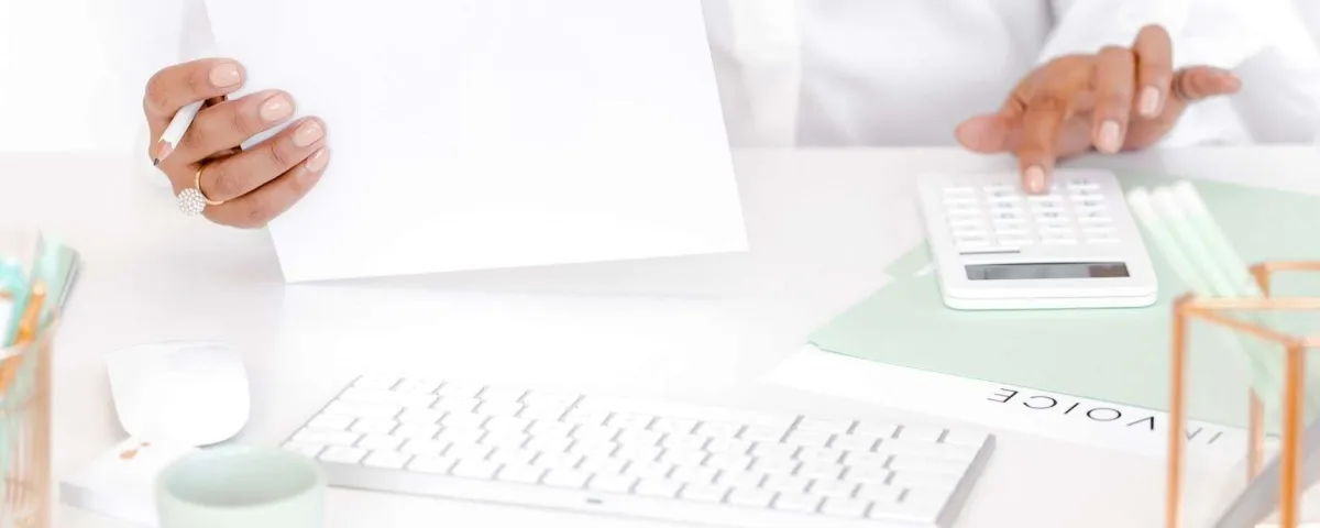 person's hands doing paperwork with an invoice showing on the desk "5 More Money-Making Activities Coaches, Consultants, and Service-Business Owners Should Be Doing"