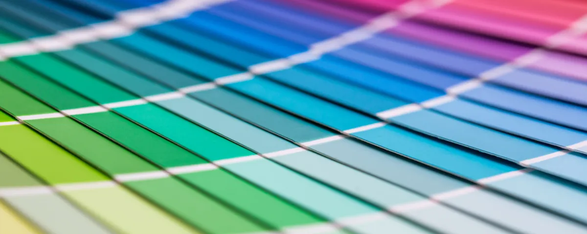 A fanned-out paint swatch book showing a gradient of greens, blues, purples and pinks.