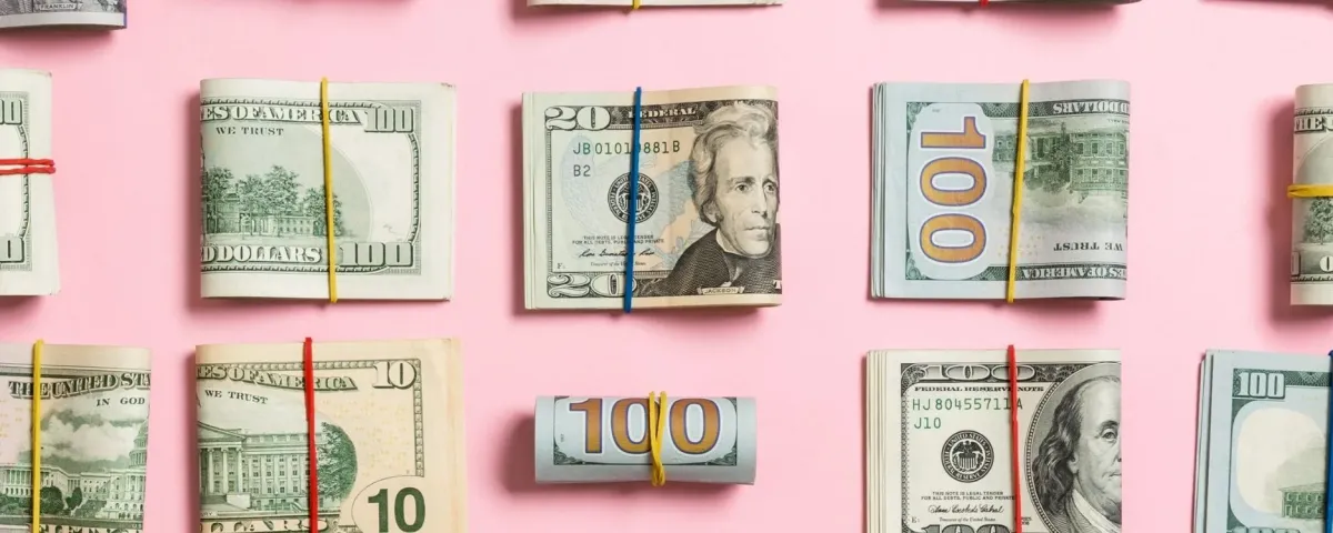 folded wads of money on a pink background