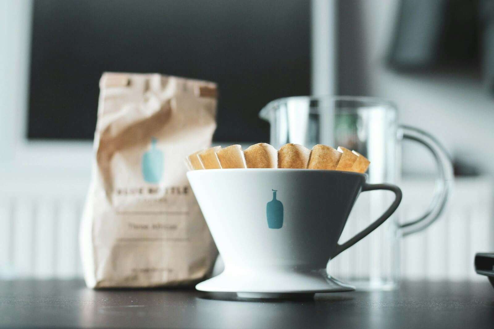 white ceramic mug with coffee filter on table