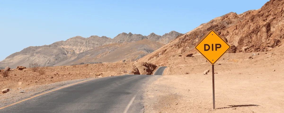 road in the desert with a street sign that says DIP don't quit