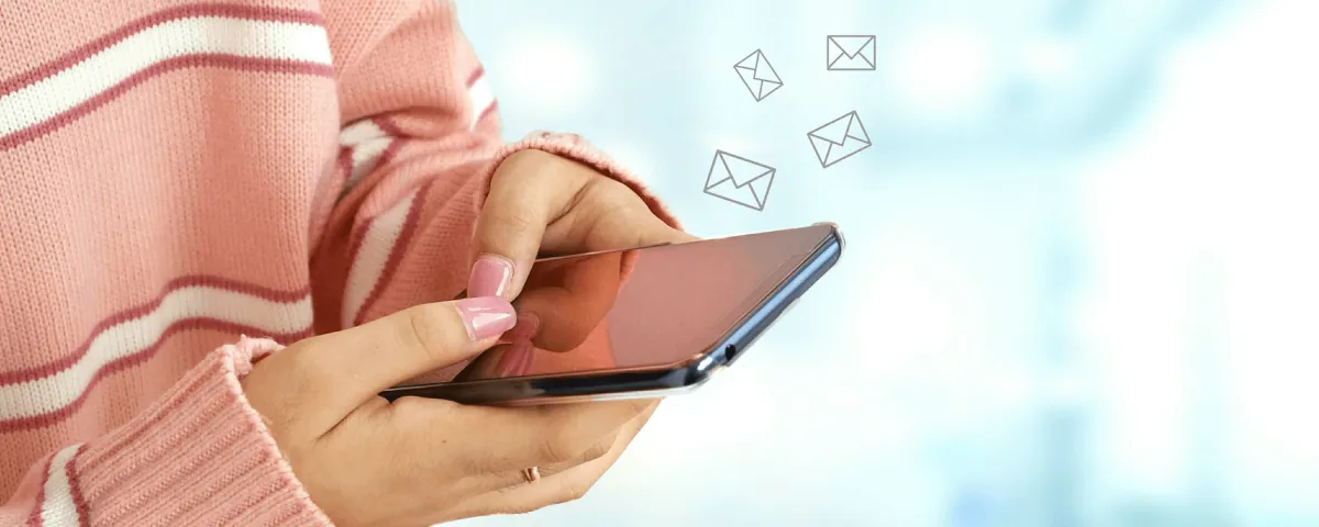 photo of a woman's hands holding a cell phone with envelope icons floating off the screen to represent effective email marketing