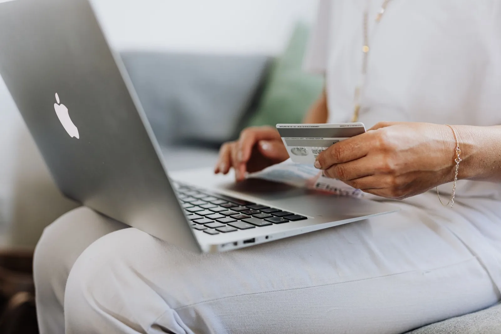 Woman holding a credit card while using a laptop to make a purchase online.