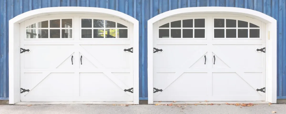 two white carriage style garage doors on a blue house.