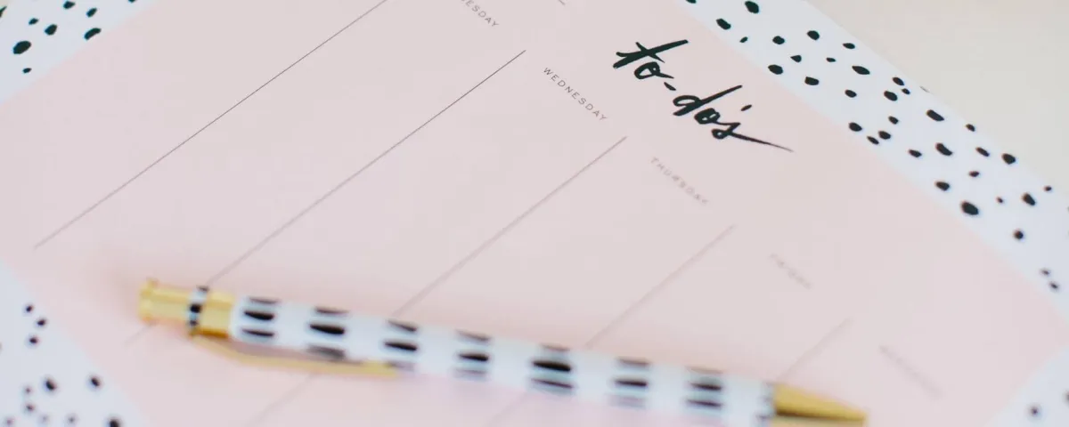 a pad of paper and a fancy pen. the paper shows a bunch of columns with the word to-do's at the top