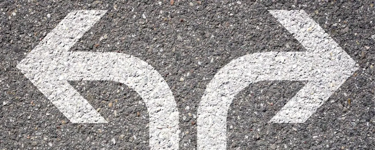 Two white arrows painted on asphalt, one curving left and one curving right.