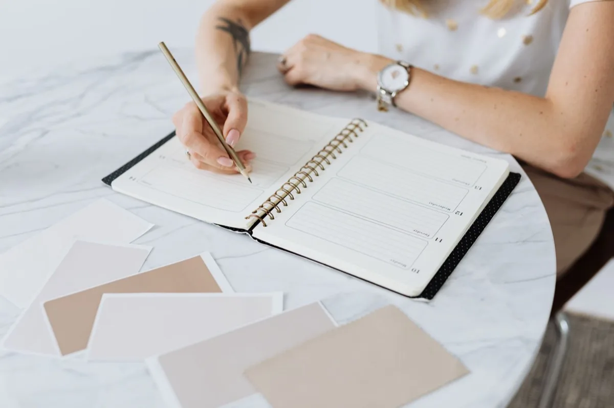 Woman writing in her planner following the mid-year marketing reset for coaches.