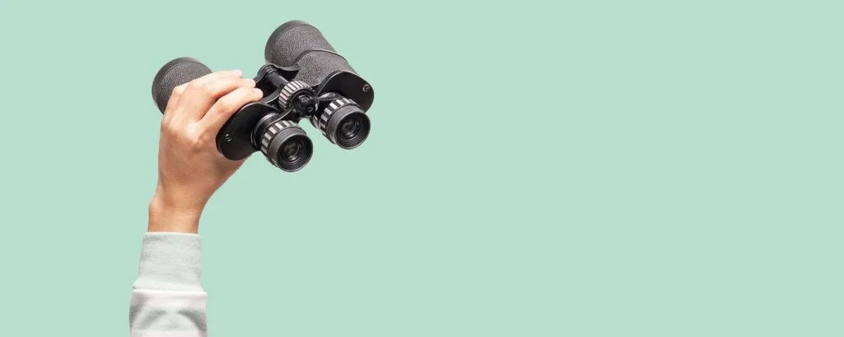 hand holding binoculars on green background for blog post "Search Engine Optimization (SEO) Resources"