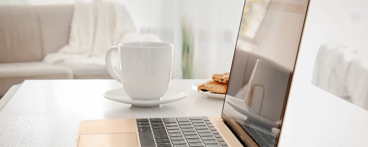 laptop and a white coffee mug on a desk