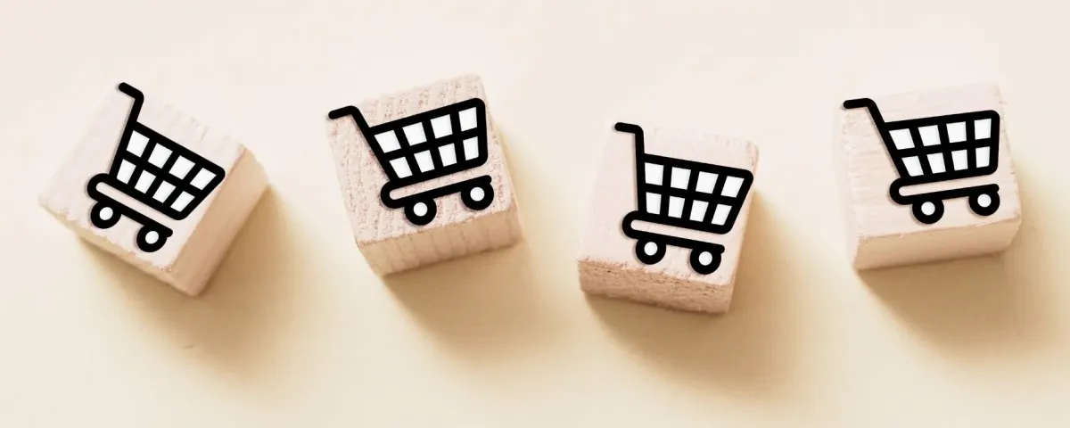 Four wooden blocks in a row, each printed with a black shopping trolley icon.