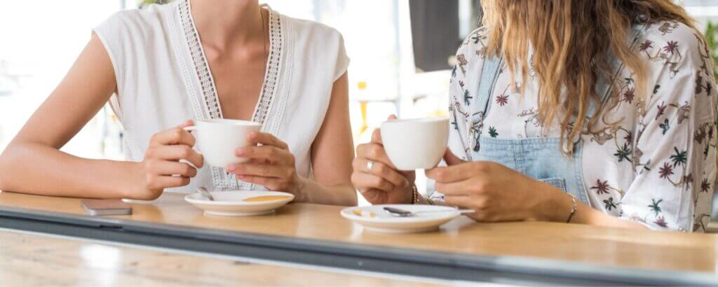 two women sitting at a counter drinking coffee together