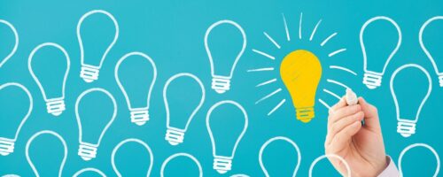 a bunch of hand drawn light bulbs with a hand filling in one of them and adding rays coming out of it showing ideas.