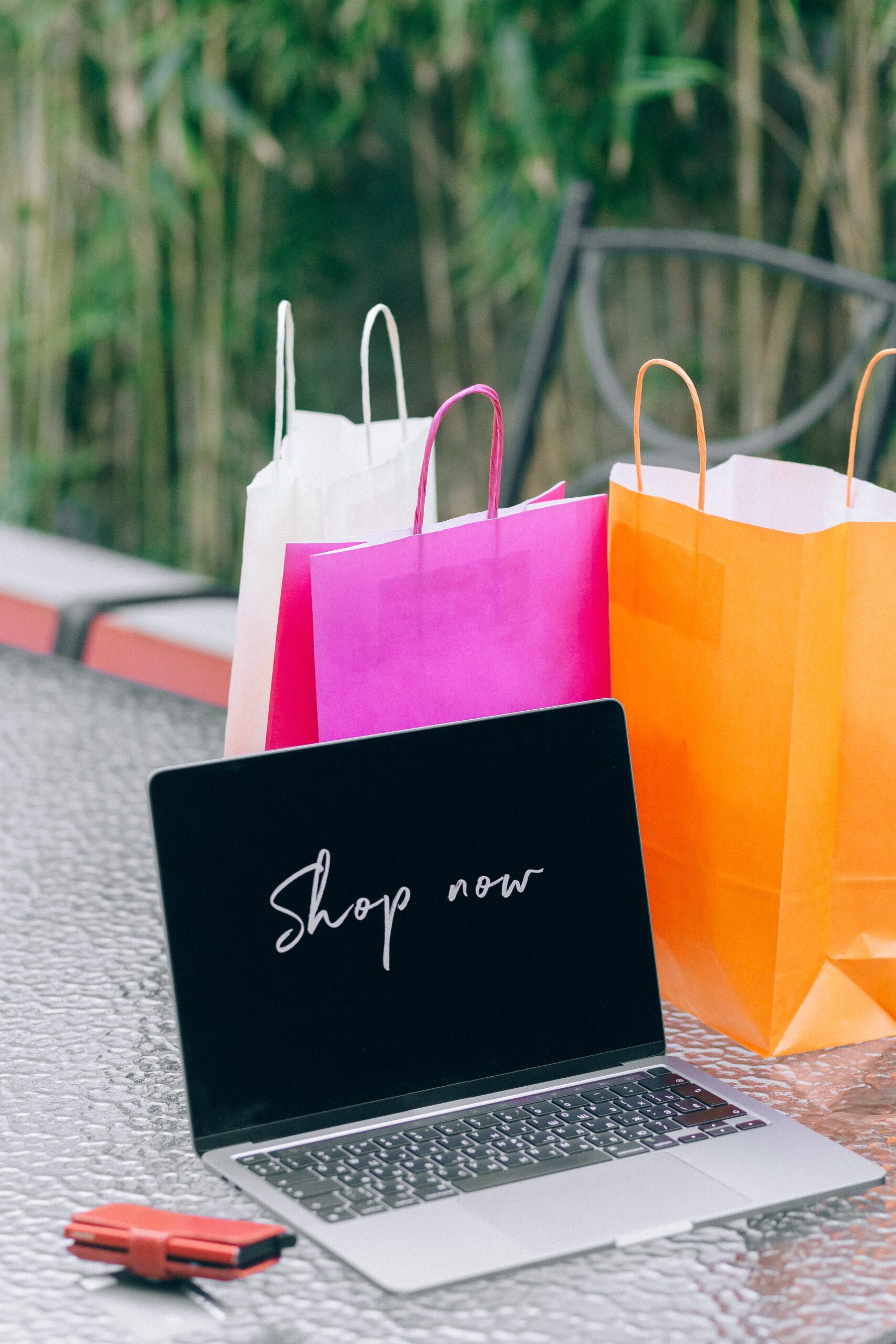 Laptop sitting on a table with gift bags. the words on the screen say, "Shop Now."