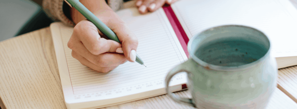 Feminine hands writing in an organizer as she sets goals using the 12 week year method