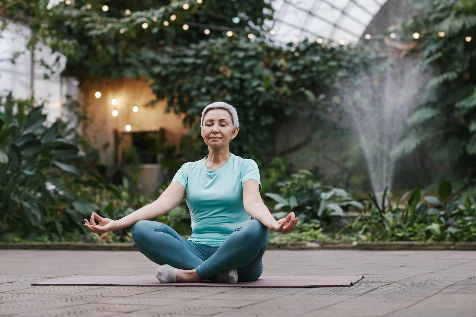 Woman meditating at an indoors botanical garden