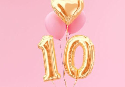 gold balloons in the shape of a number 10 on a pink background
