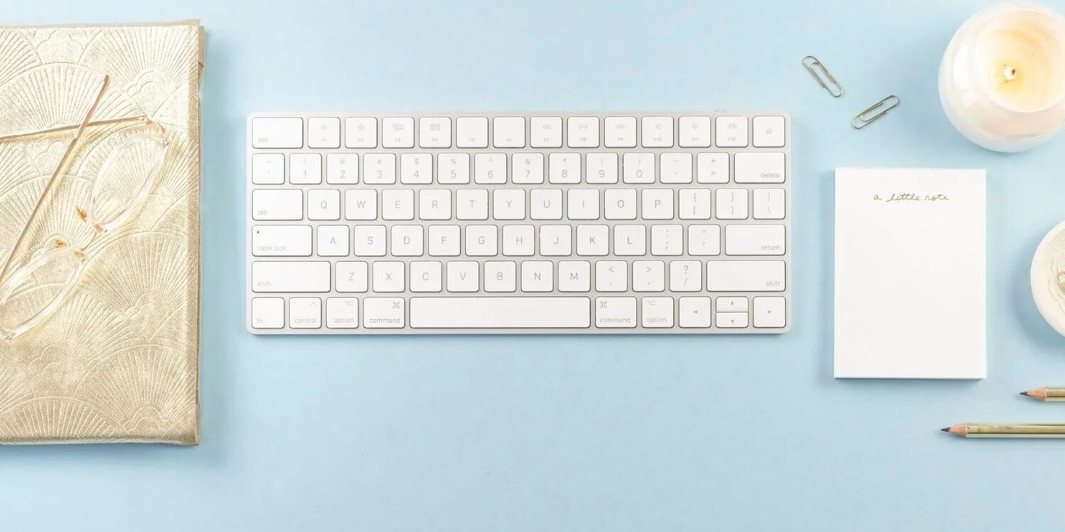 blue background with a journal, keyboard, candle and writing utensils