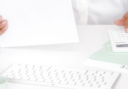 person's hands doing paperwork with an invoice showing on the desk "5 More Money-Making Activities Coaches, Consultants, and Service-Business Owners Should Be Doing"