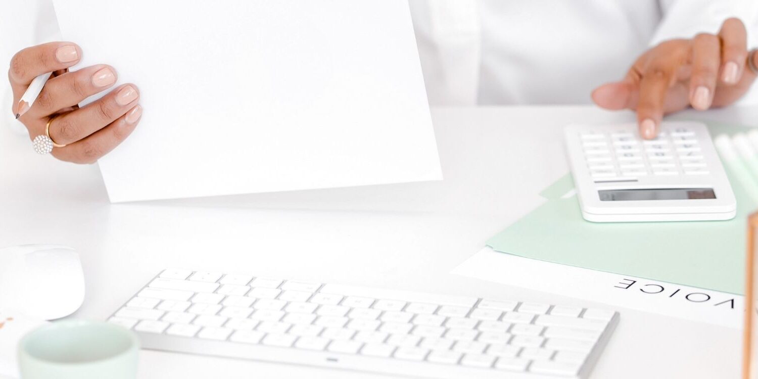 person's hands doing paperwork with an invoice showing on the desk "5 More Money-Making Activities Coaches, Consultants, and Service-Business Owners Should Be Doing"