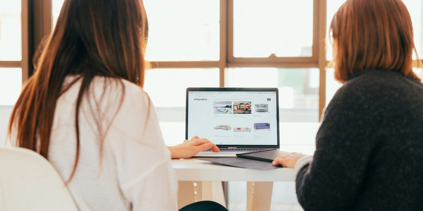 two women talking while looking at laptop computer