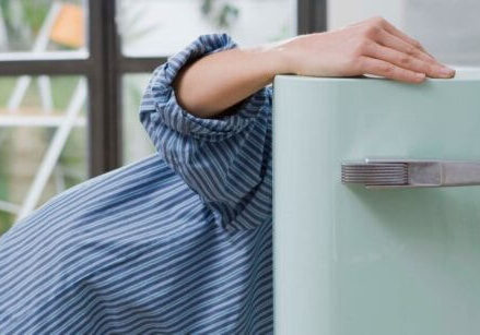woman opening the door to a refrigerator and looking inside