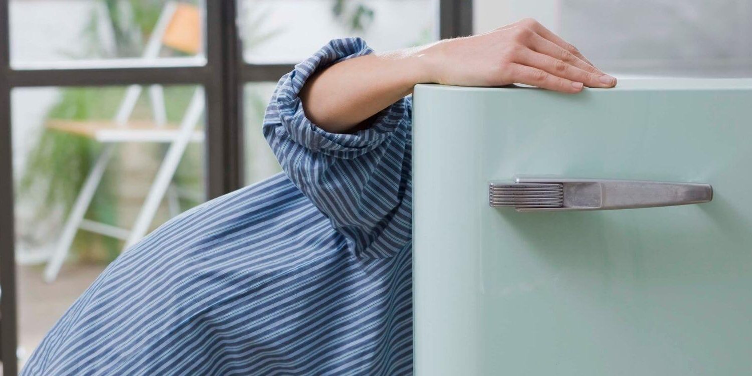 woman opening the door to a refrigerator and looking inside