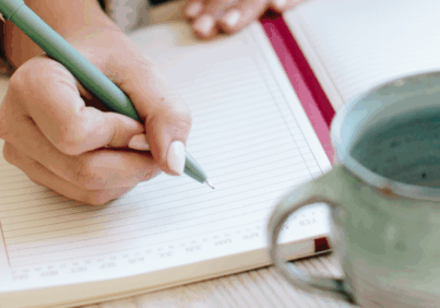 Feminine hands writing in an organizer as she sets goals using the 12 week year method