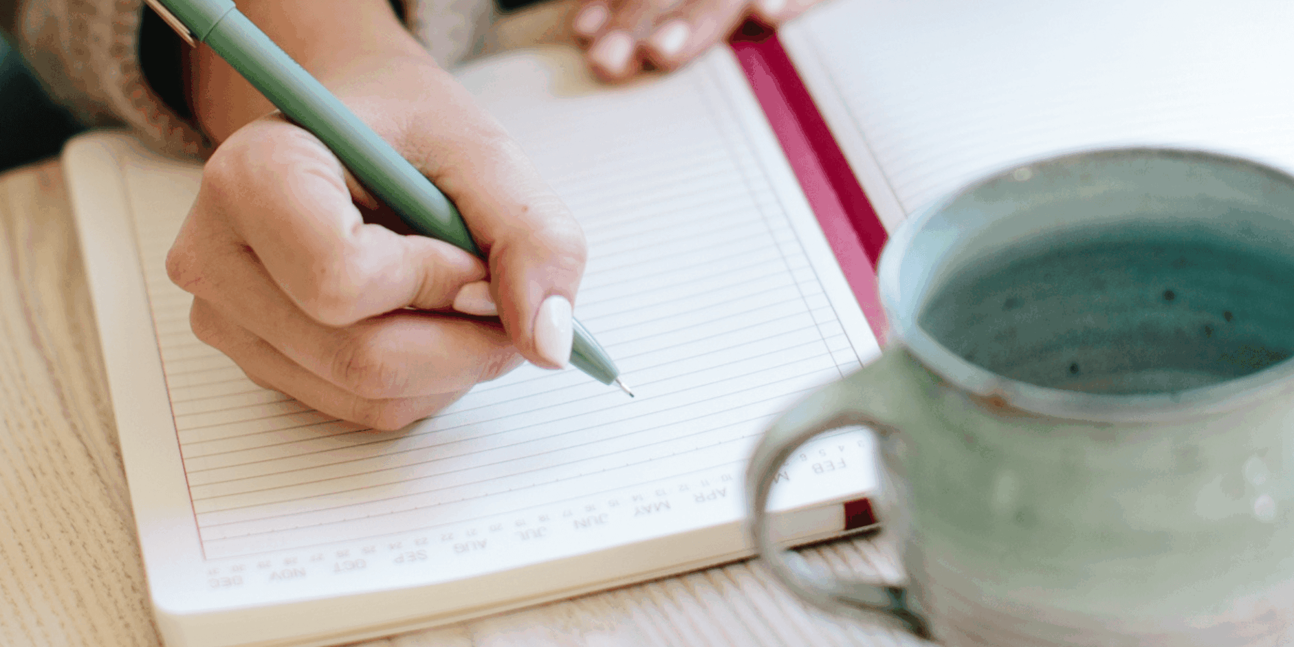 Feminine hands writing in an organizer as she sets goals using the 12 week year method
