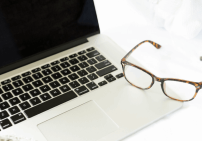 A paiur of glasses sitting on the keyboard of a laptop