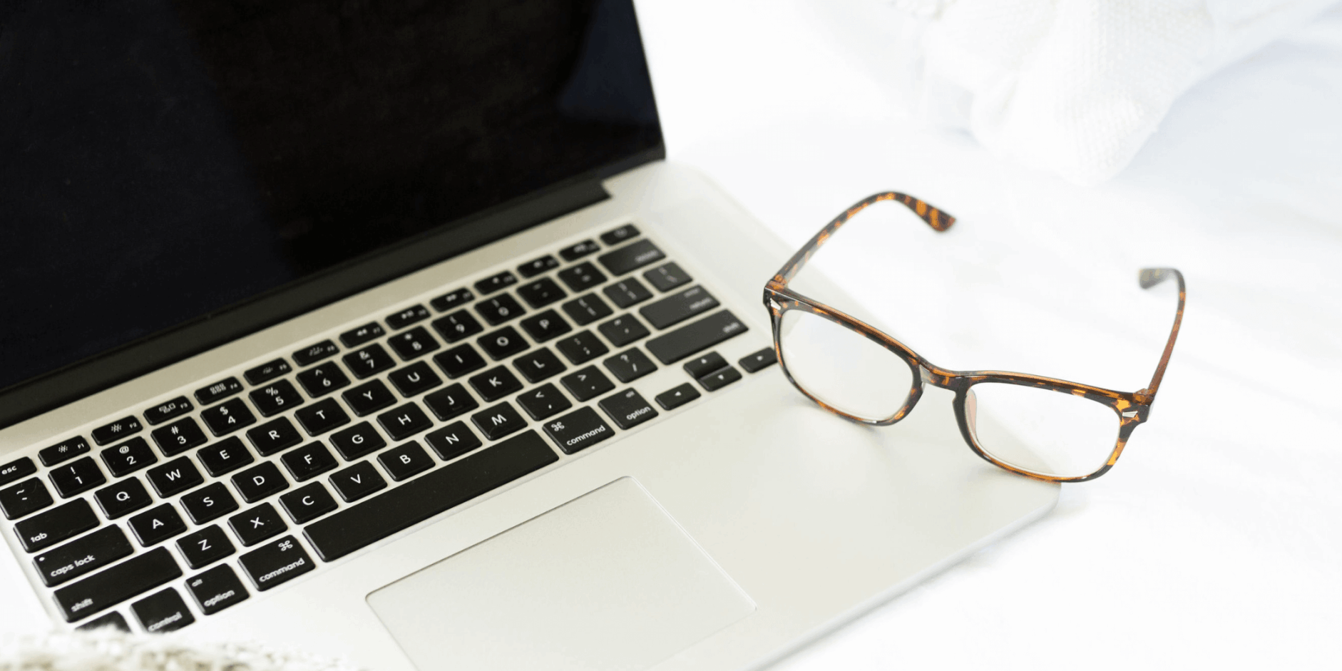 A paiur of glasses sitting on the keyboard of a laptop