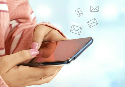 photo of a woman's hands holding a cell phone with envelope icons floating off the screen to represent effective email marketing