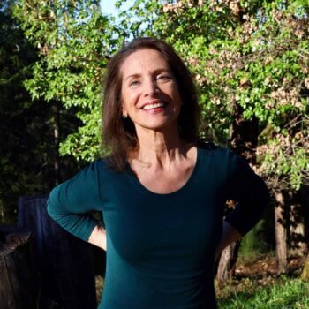 Ginny cutler - woman with long brown hair wearing a green top outside with trees in the background