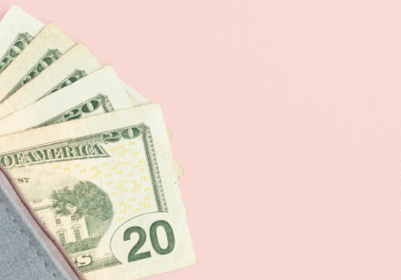 Money peeking out of a zippered case with a pink background. Hidden costs.