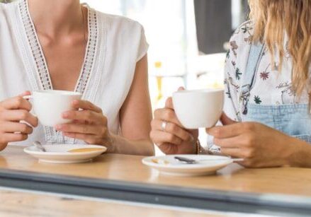 two women sitting at a counter drinking coffee together