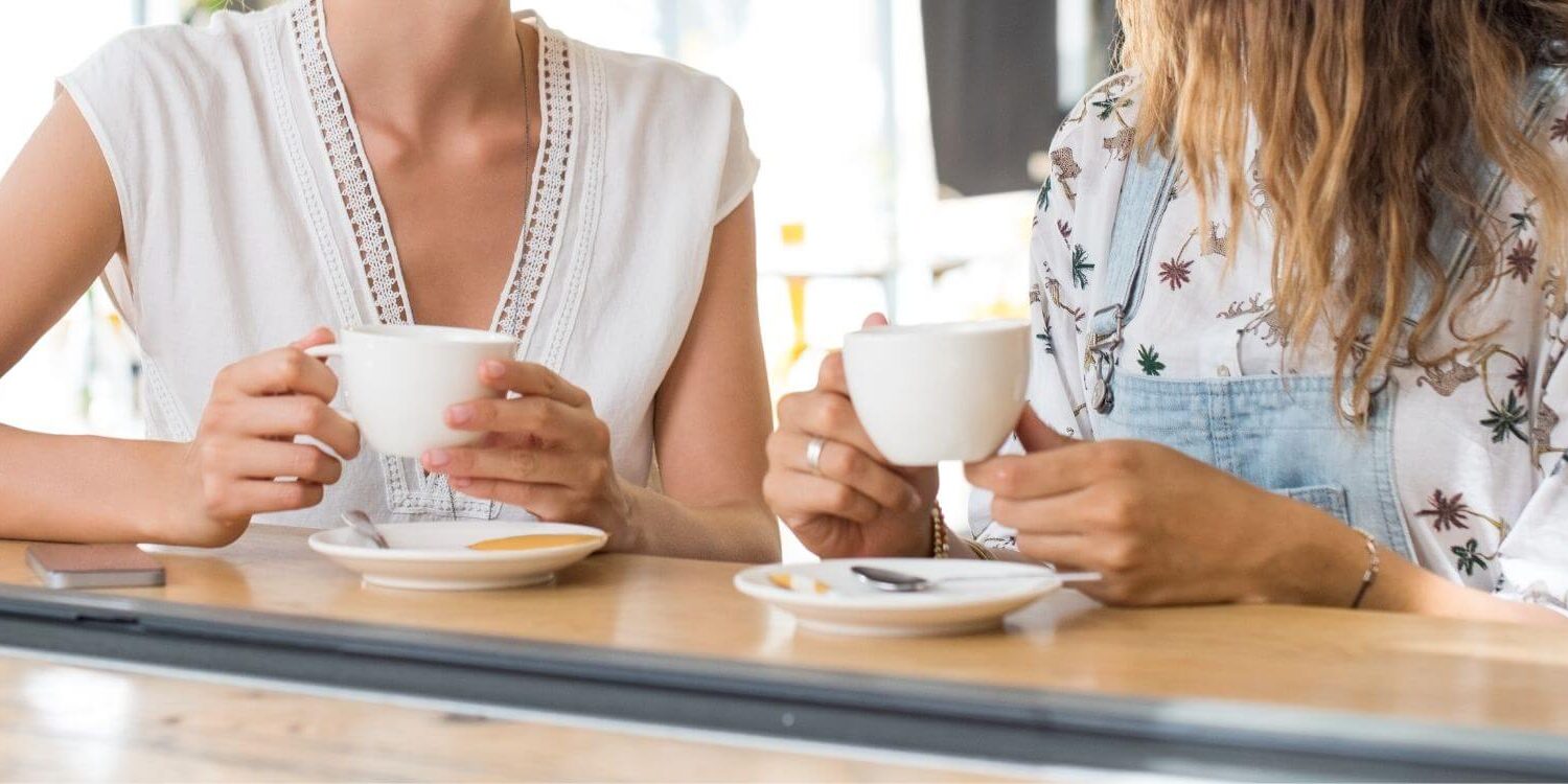 two women sitting at a counter drinking coffee together