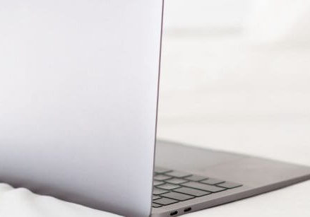 laptop on a bed with pens and pencils
