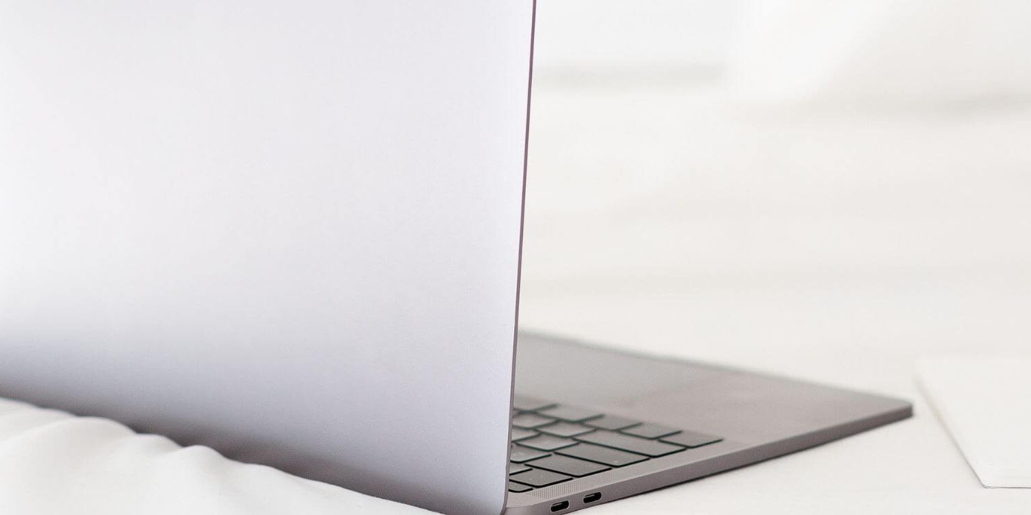 laptop on a bed with pens and pencils