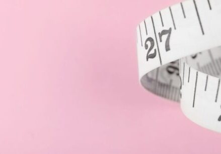 flexible tape measure curled in a ribbon spiral on a pink background
