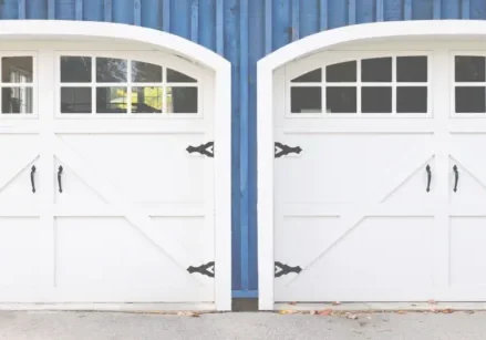 two white carriage style garage doors on a blue house.