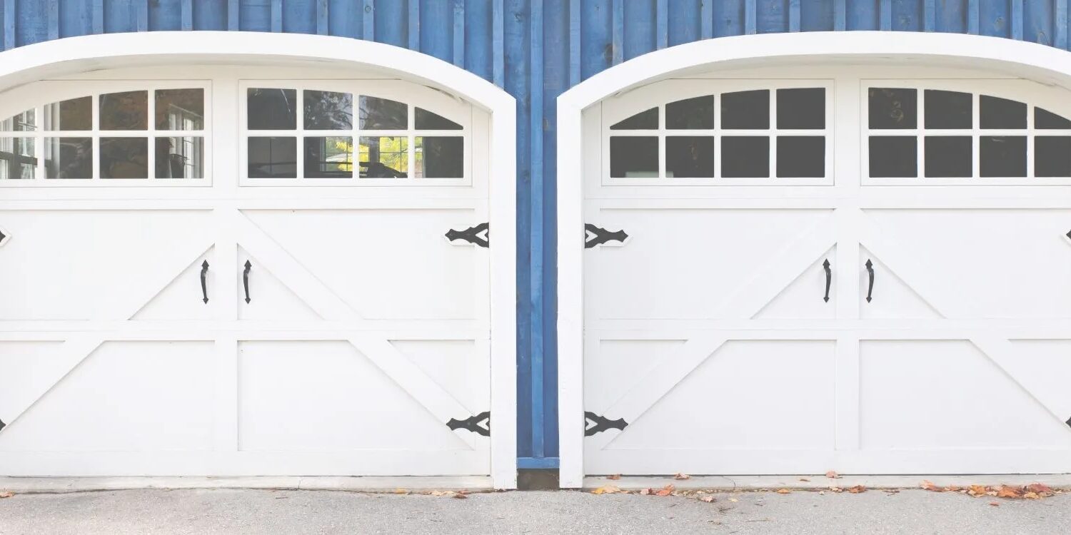 two white carriage style garage doors on a blue house.