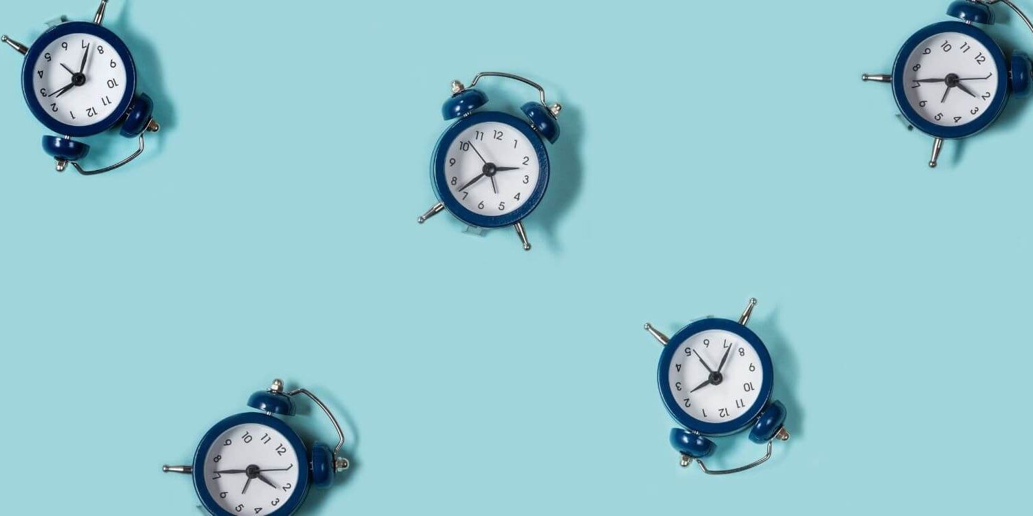 a bunch of navy blue alarm clocks scattered on a turquoise background