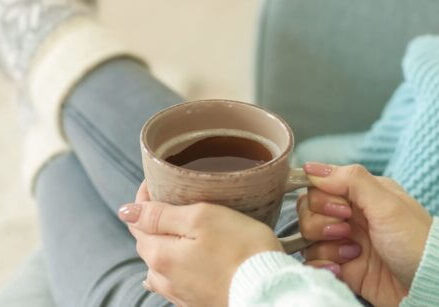 woman relaxing on a sofa wearing fuzzy socks and holding a warm cup of coffee or tea