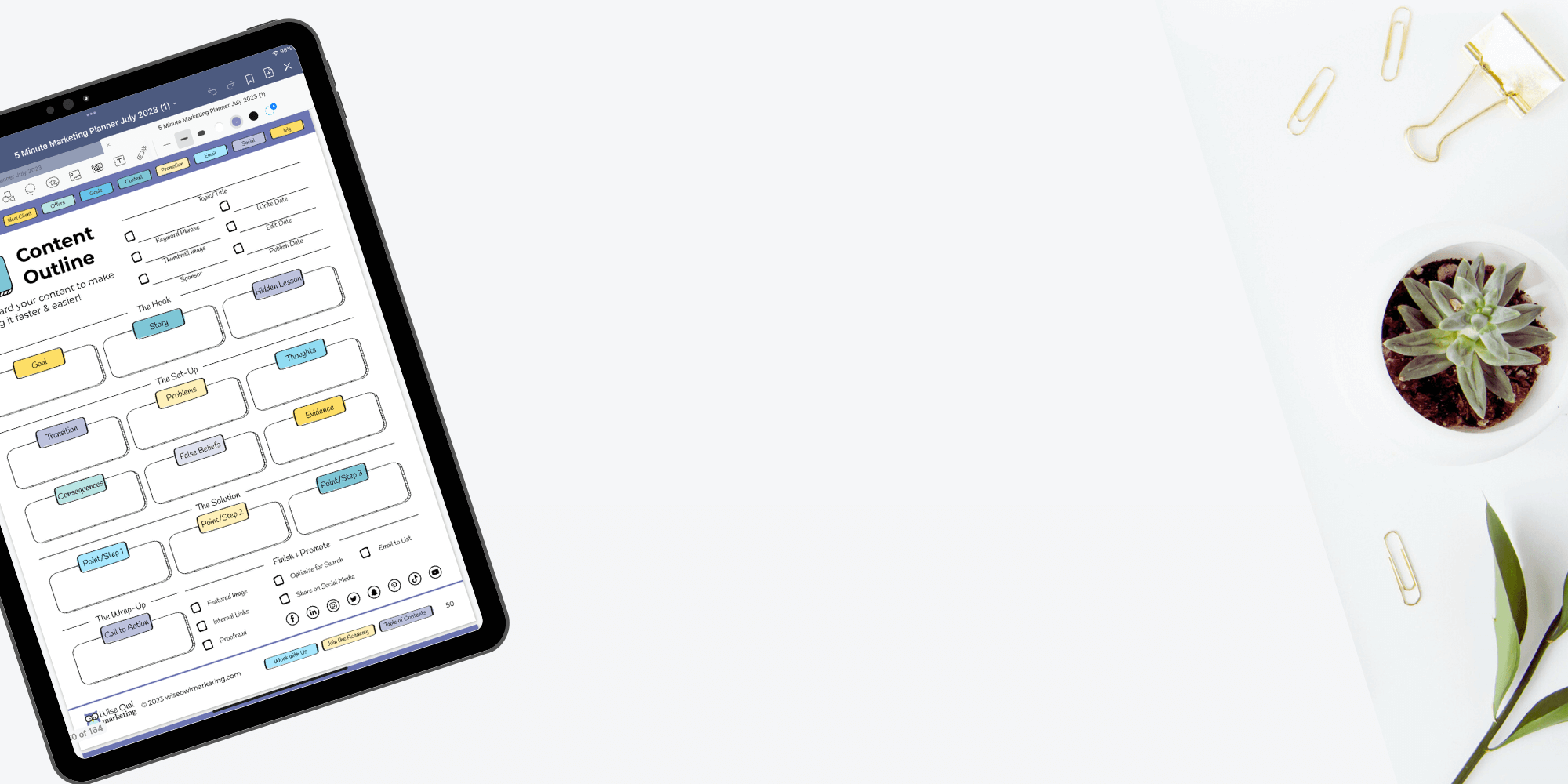 marketing planner on a desk with a plant and paper clips