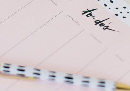 a pad of paper and a fancy pen. the paper shows a bunch of columns with the word to-do's at the top