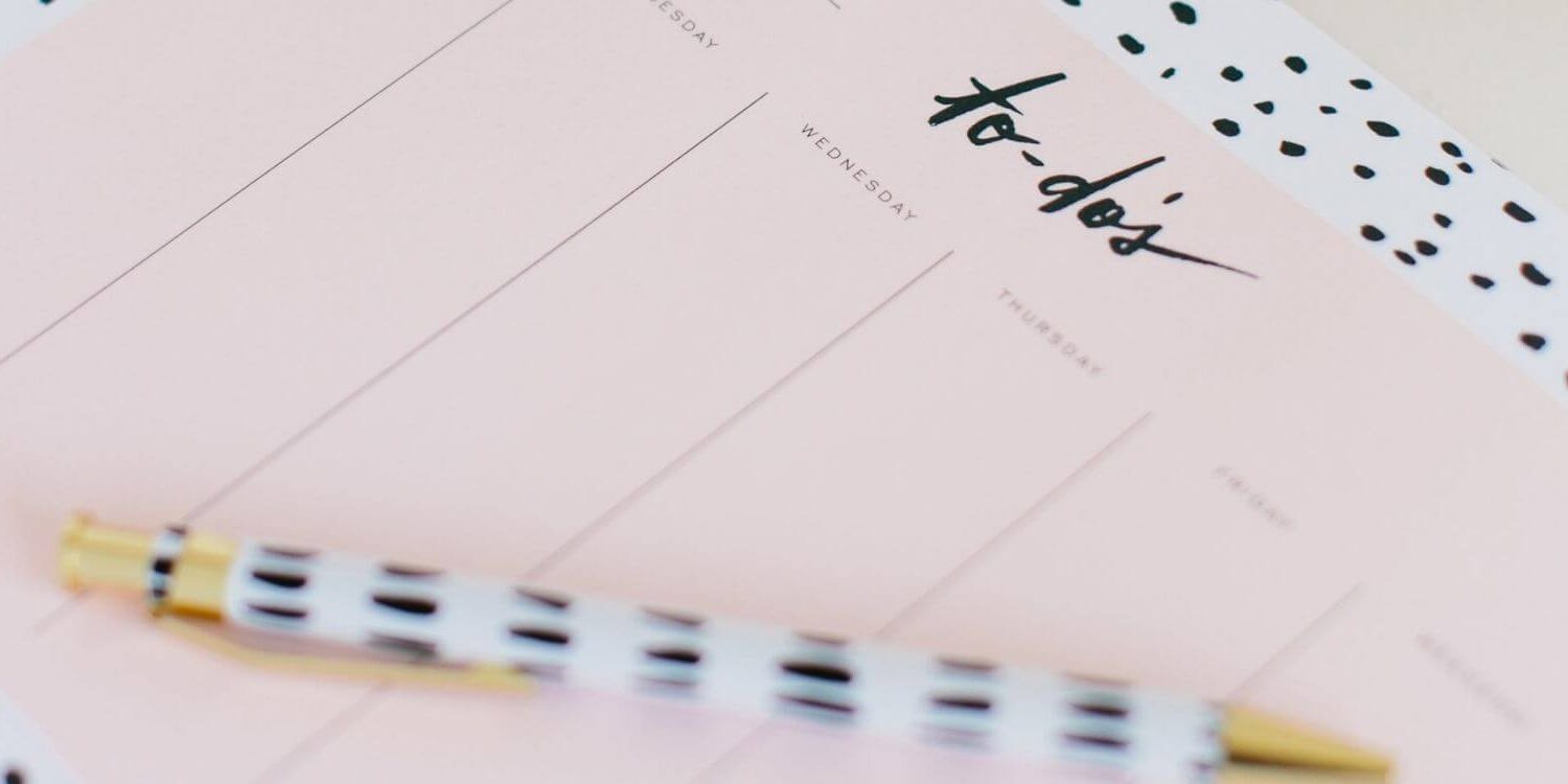 a pad of paper and a fancy pen. the paper shows a bunch of columns with the word to-do's at the top