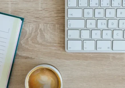 A notepad, keyboard, and coffee cup ready to write a blog post