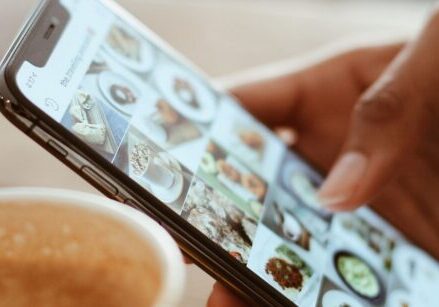 Person's hand scrolling through content on their phone. "How to Promote Content Efficiently and Effectively"