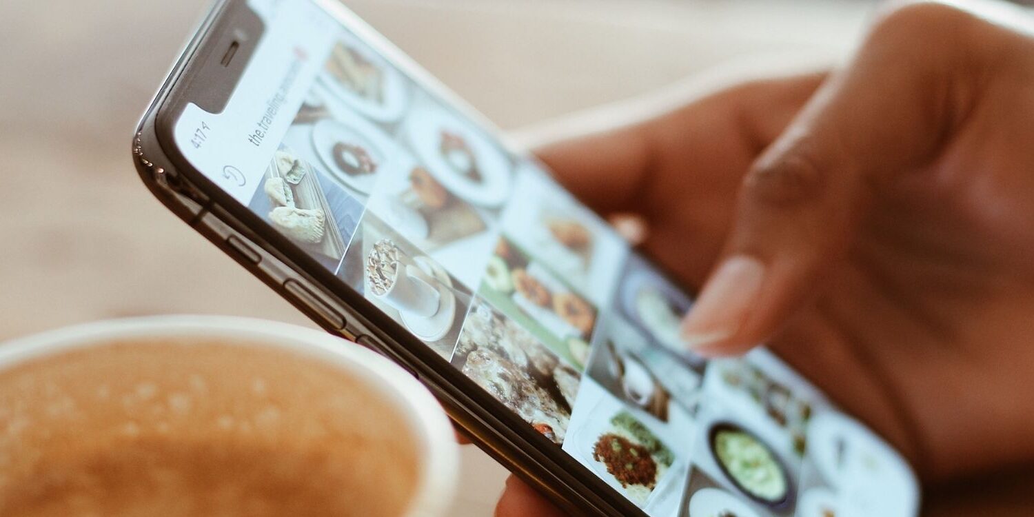 Person's hand scrolling through content on their phone. "How to Promote Content Efficiently and Effectively"