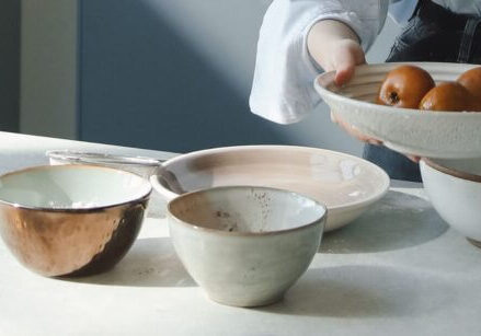 woman recording a video of herself making a batch of cookies with her cellphone on a tripod on the counter with a bunch of bowls full of ingredients